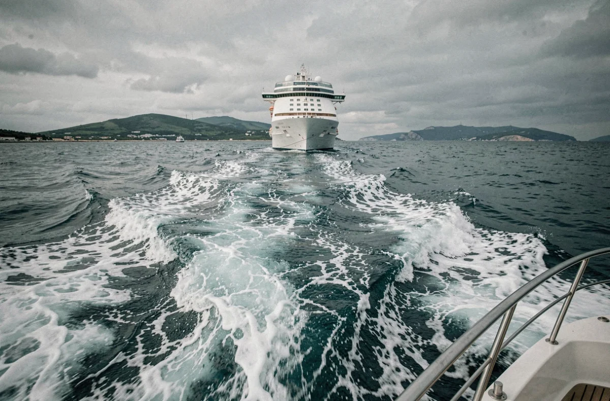 Navire de croisière s'éloignant de Toulon vu depuis la mer avec le sillage d'écume