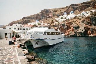 Ferry blanc amarré au port de Folégandros avec des bâtiments blanchis à la chaux sur fond de falaises rocheuses des Cyclades